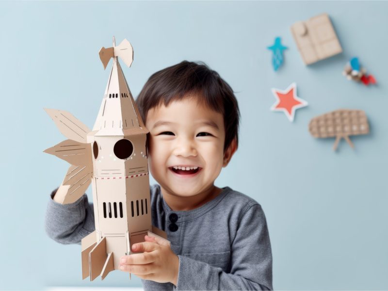 A boy is holding a cardboard rocket that